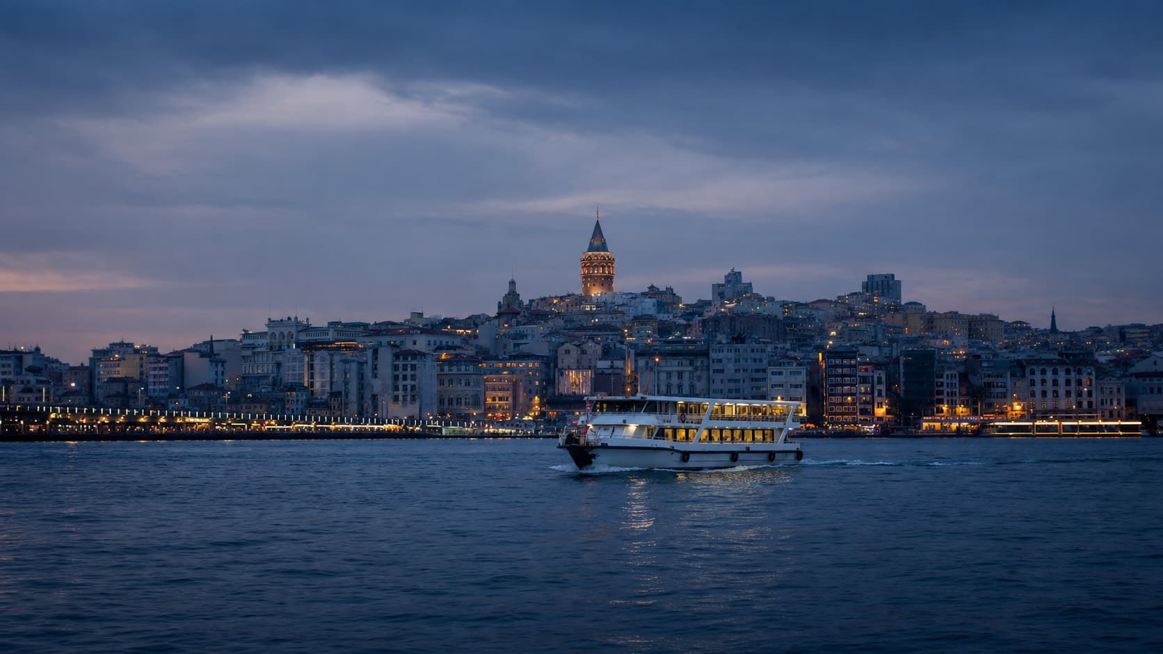 Mavi saatte Galata Kulesi, Karaköy kıyısı ve Haliç ağzında ilerleyen yolcu vapuru